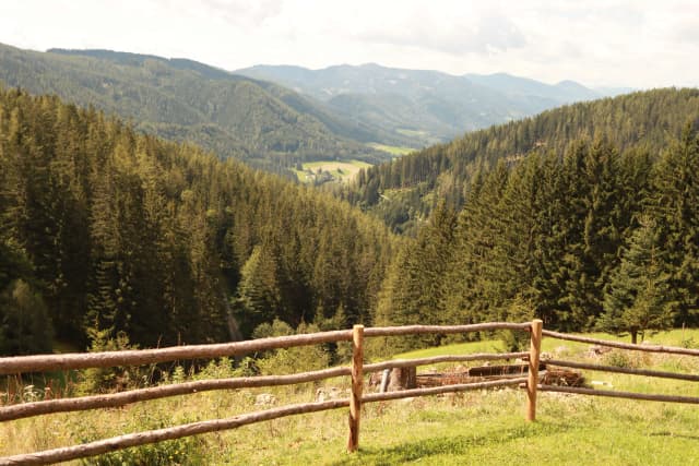 A breathtaking view of lush green hills and a rustic wooden fence in the foreground.