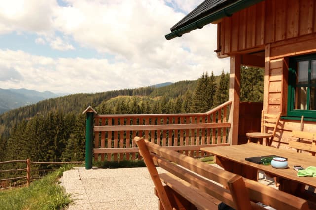A cozy wooden cabin terrace overlooking a serene forest landscape.