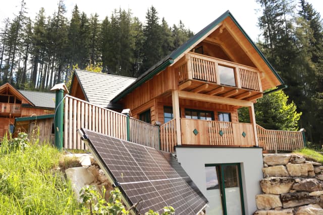 A solar-powered cabin surrounded by nature and tall trees.